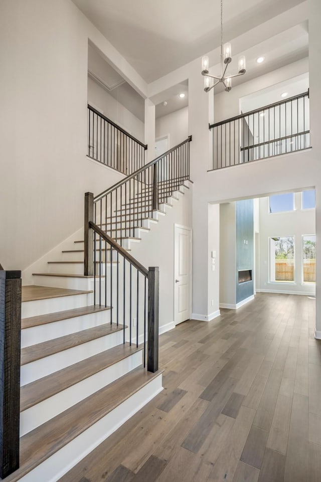 9722 Leafgate Ct, Missouri City, TX 77459 - staircase featuring wood finished floors, recessed lighting, a notable chandelier, and a high ceiling