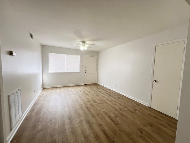 empty room with visible vents, ceiling fan, and wood finished floors