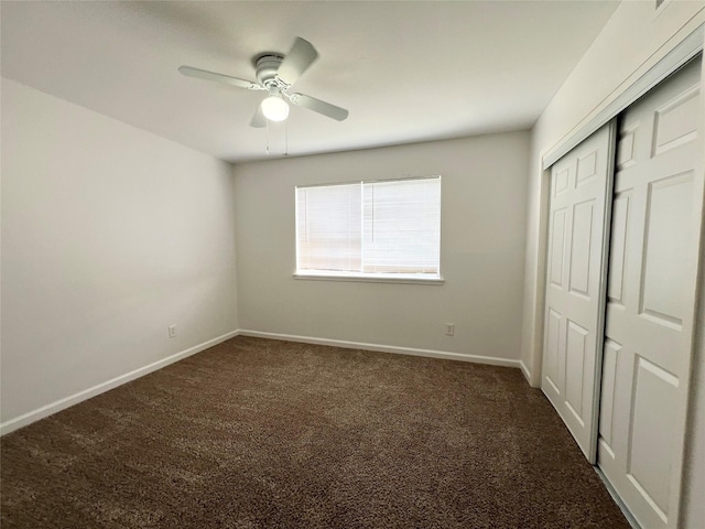 unfurnished bedroom featuring a closet, a ceiling fan, dark colored carpet, and baseboards