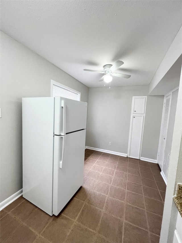 kitchen featuring a ceiling fan, freestanding refrigerator, and baseboards