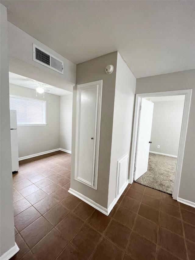 corridor with baseboards, visible vents, and dark tile patterned floors