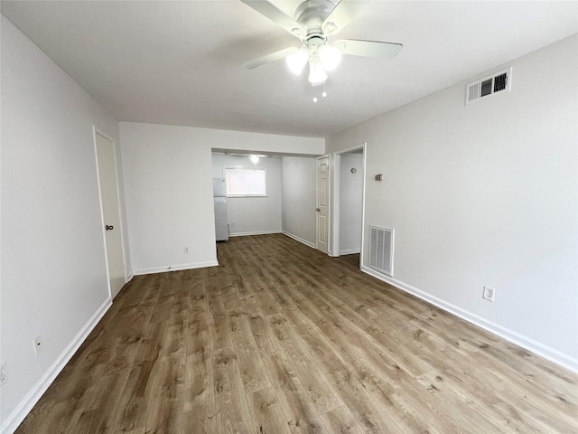 empty room with wood finished floors, visible vents, ceiling fan, and baseboards