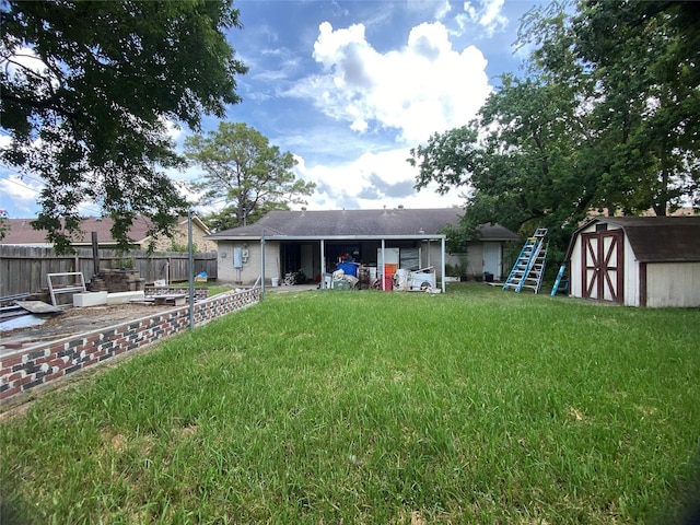 back of property featuring fence, an outdoor structure, a storage shed, roof with shingles, and a lawn