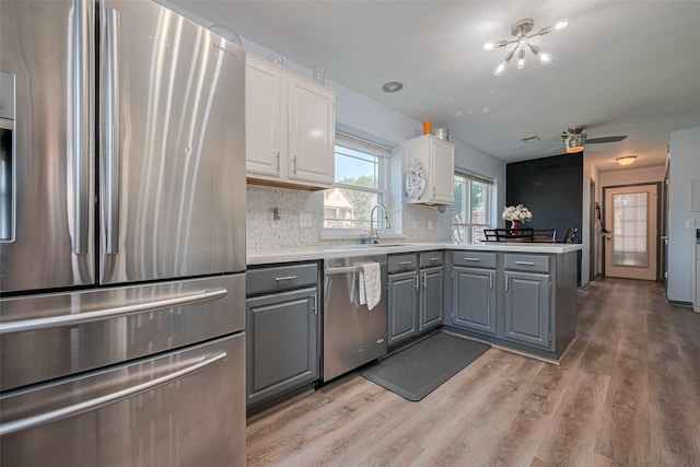 17022 Shadow Valley Dr, Spring, TX 77379 - kitchen featuring stainless steel appliances, gray cabinetry, light wood-style floors, white cabinets, and a peninsula