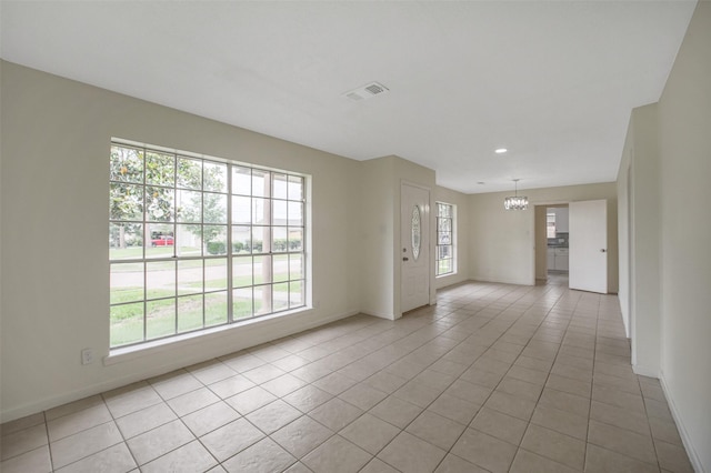 spare room featuring visible vents, baseboards, light tile patterned floors, and a notable chandelier