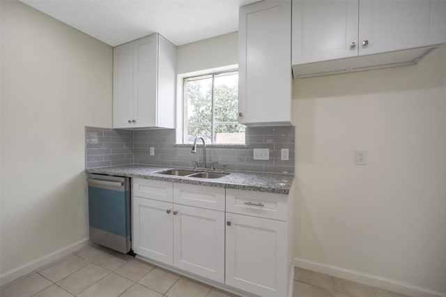 kitchen with baseboards, dishwashing machine, white cabinets, tasteful backsplash, and a sink