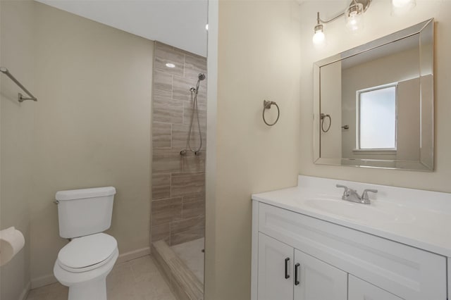bathroom with vanity, toilet, baseboards, tiled shower, and tile patterned floors