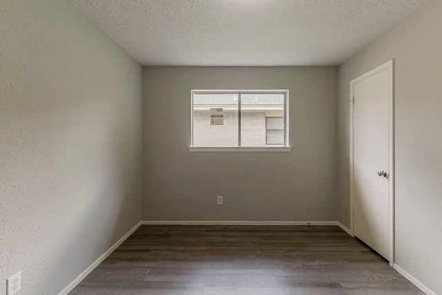 empty room with a textured ceiling, wood finished floors, and baseboards