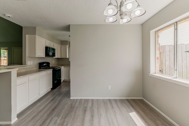 kitchen with light countertops, white cabinets, black appliances, light wood finished floors, and a textured ceiling