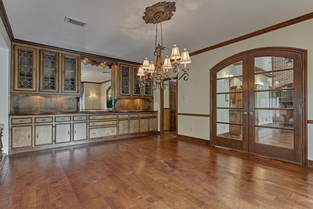 unfurnished dining area with dark wood-type flooring, arched walkways, french doors, and ornamental molding