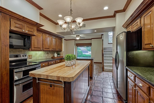kitchen with ornamental molding, butcher block countertops, tasteful backsplash, ceiling fan with notable chandelier, and stainless steel appliances