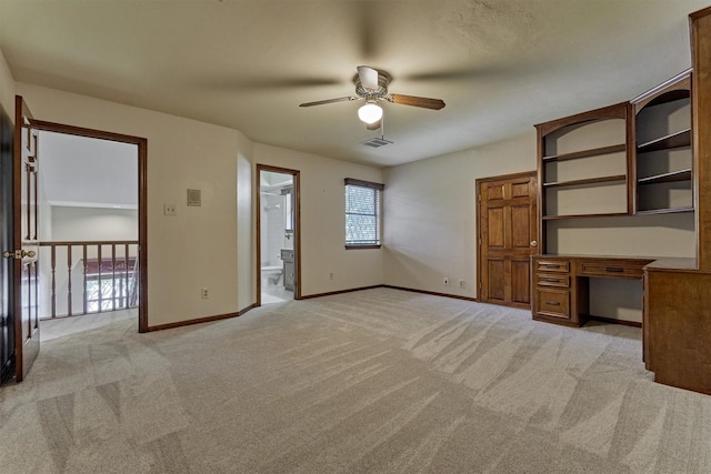 interior space featuring ceiling fan, light colored carpet, built in desk, baseboards, and visible vents