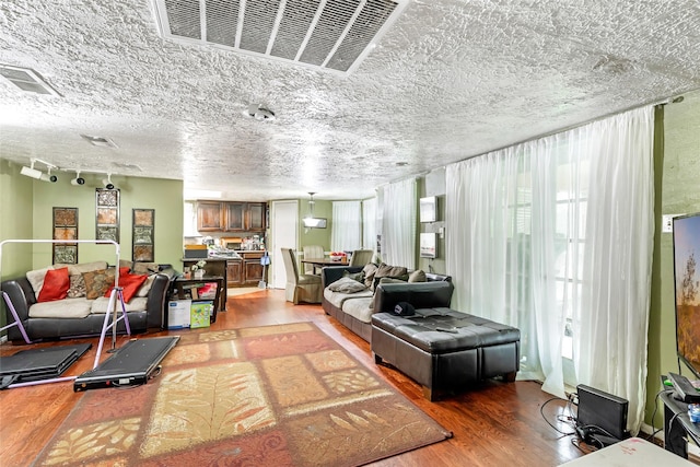 living area with visible vents, a textured ceiling, and light wood finished floors