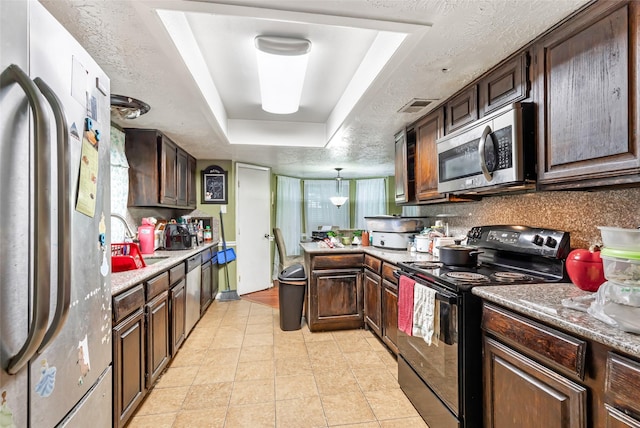 kitchen featuring stainless steel appliances, a sink, visible vents, a raised ceiling, and a peninsula