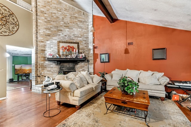 living room featuring beam ceiling, wood finished floors, high vaulted ceiling, and a brick fireplace