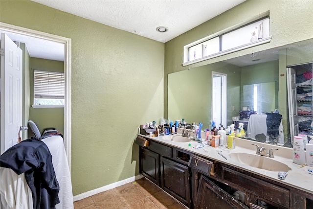 full bathroom with a textured wall, baseboards, and a sink