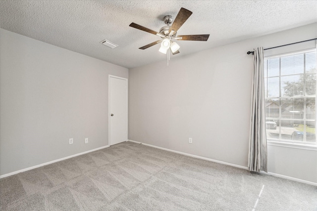 carpeted empty room with a textured ceiling, ceiling fan, visible vents, and baseboards