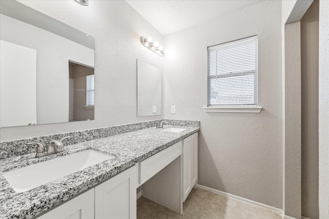 full bathroom with double vanity, baseboards, tile patterned flooring, and a sink