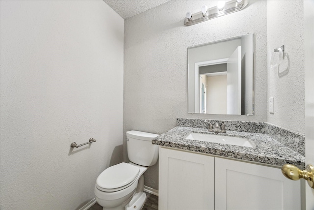 bathroom featuring toilet, a textured ceiling, and vanity