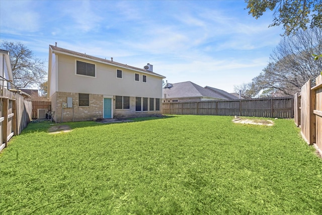 rear view of house featuring brick siding, a fenced backyard, and a lawn