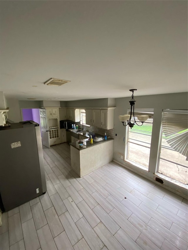 22006 Joshua Kendell Ln, Katy, TX 77449 - kitchen with a peninsula, dark countertops, tasteful backsplash, wood finish floors, and freestanding refrigerator
