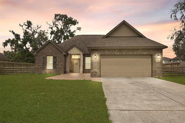 view of front facade with fence, a yard, and brick siding