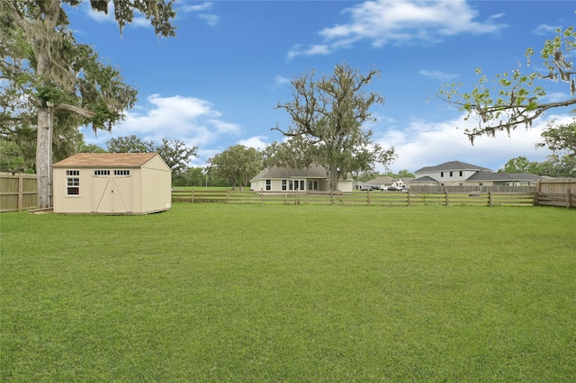 view of yard featuring an outbuilding, a storage unit, and a fenced backyard