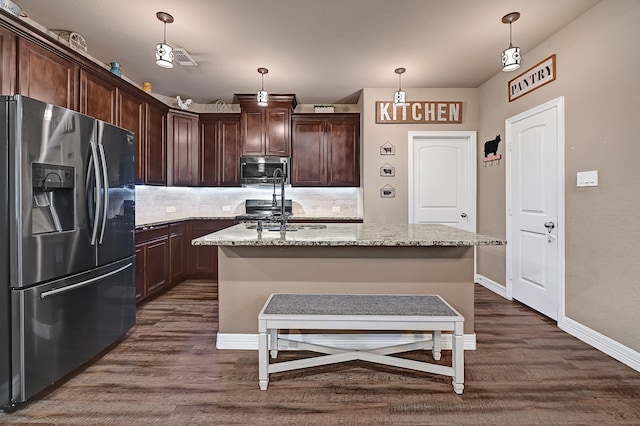 kitchen with tasteful backsplash, appliances with stainless steel finishes, dark wood-style floors, dark brown cabinetry, and light stone countertops