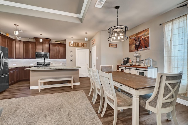 dining space featuring dark wood-style floors, visible vents, a notable chandelier, and crown molding