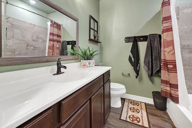 bathroom with toilet, wood finished floors, vanity, and baseboards