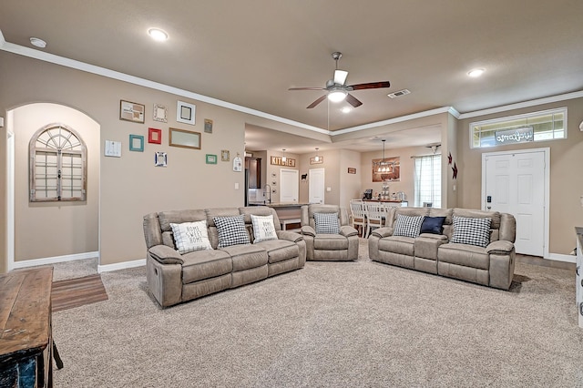 living room featuring baseboards, ornamental molding, ceiling fan, and carpet floors