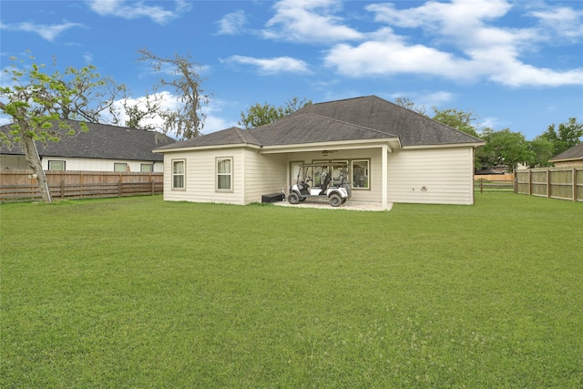 back of property with roof with shingles, a yard, and a fenced backyard