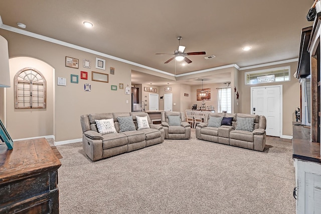 carpeted living room with ornamental molding, arched walkways, ceiling fan, and baseboards