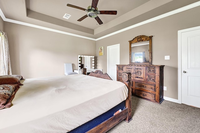 bedroom featuring visible vents, a tray ceiling, baseboards, carpet floors, and a ceiling fan