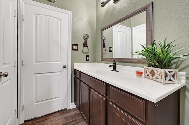 bathroom with wood finished floors, a textured wall, and vanity