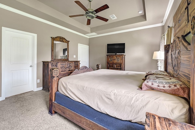 bedroom with carpet floors, visible vents, a ceiling fan, crown molding, and a tray ceiling