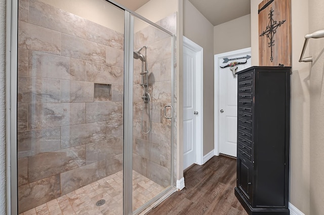 full bathroom featuring wood finished floors, a shower stall, and baseboards