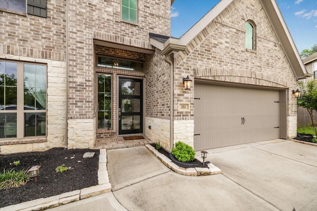 view of exterior entry with brick siding, a garage, stone siding, and concrete driveway