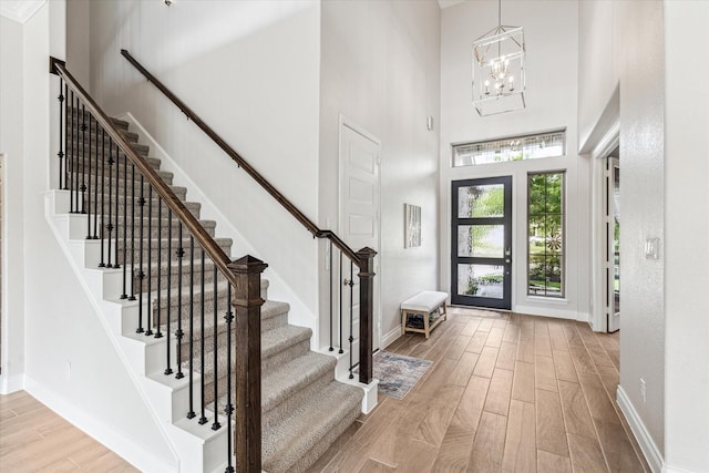 foyer entrance with stairs, a high ceiling, baseboards, and light wood finished floors