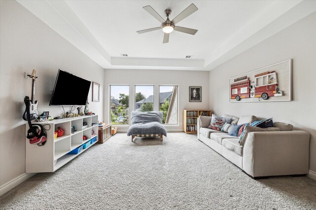 living area with visible vents, a ceiling fan, a tray ceiling, and carpet flooring