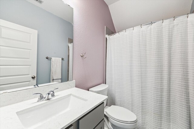 full bath with vanity, a textured wall, and toilet