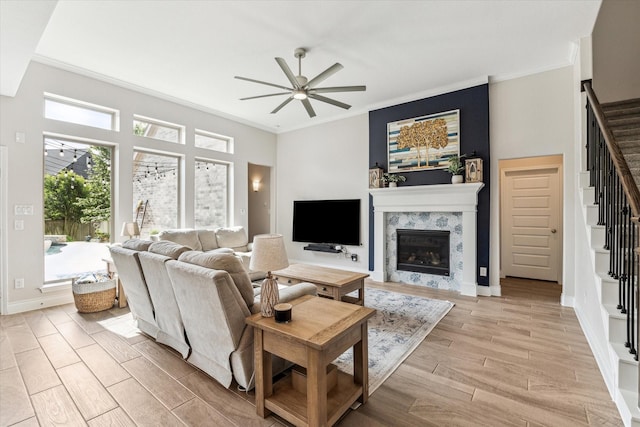 living area with crown molding, a ceiling fan, stairway, and light wood-type flooring