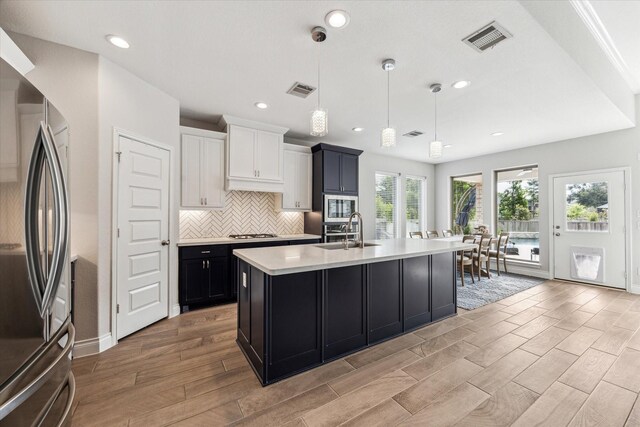 kitchen featuring visible vents, light wood-style floors, light countertops, a sink, and appliances with stainless steel finishes