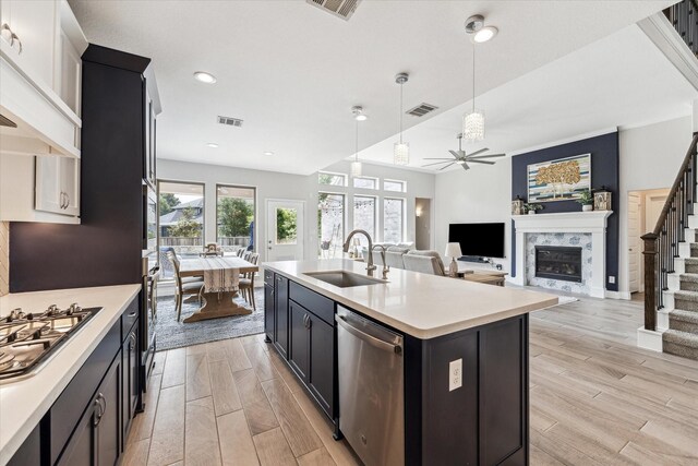 kitchen with a sink, a fireplace, light countertops, stainless steel appliances, and visible vents