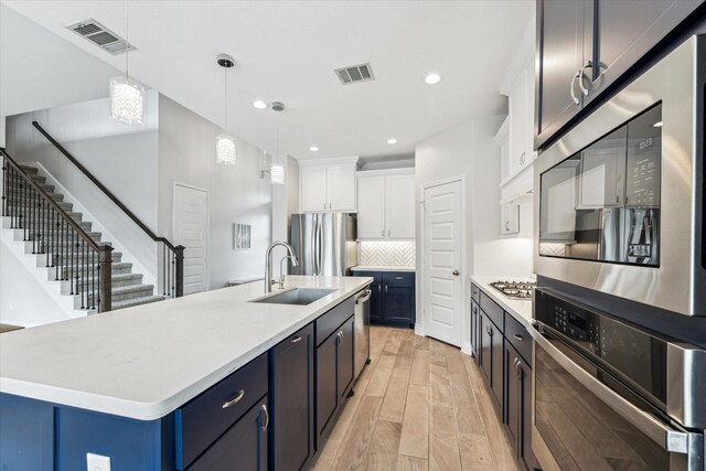 kitchen with a sink, light countertops, stainless steel appliances, and visible vents