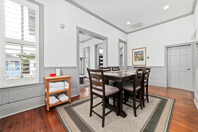 dining room with visible vents, wainscoting, wood-type flooring, and crown molding