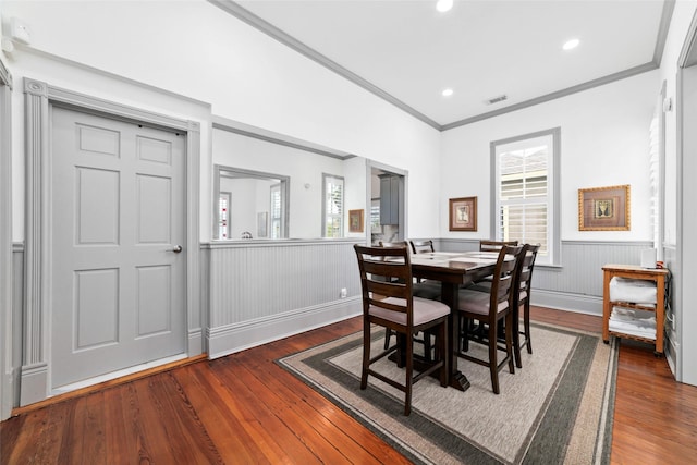 dining room featuring wood-type flooring, a wainscoted wall, and ornamental molding