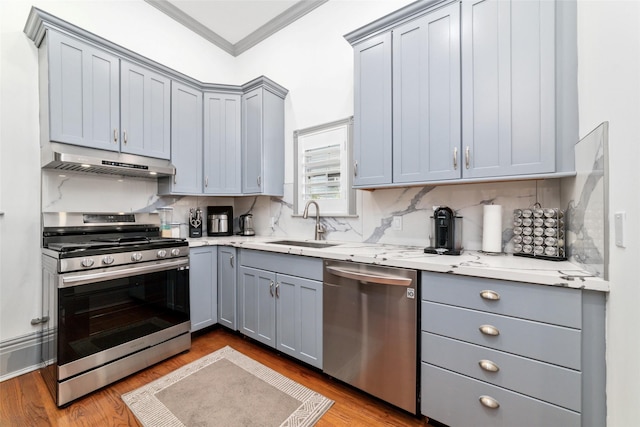 kitchen featuring tasteful backsplash, gray cabinets, appliances with stainless steel finishes, under cabinet range hood, and crown molding