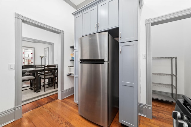 kitchen with wood finished floors, gray cabinetry, and freestanding refrigerator