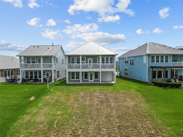 rear view of property featuring metal roof, driveway, a yard, and a balcony